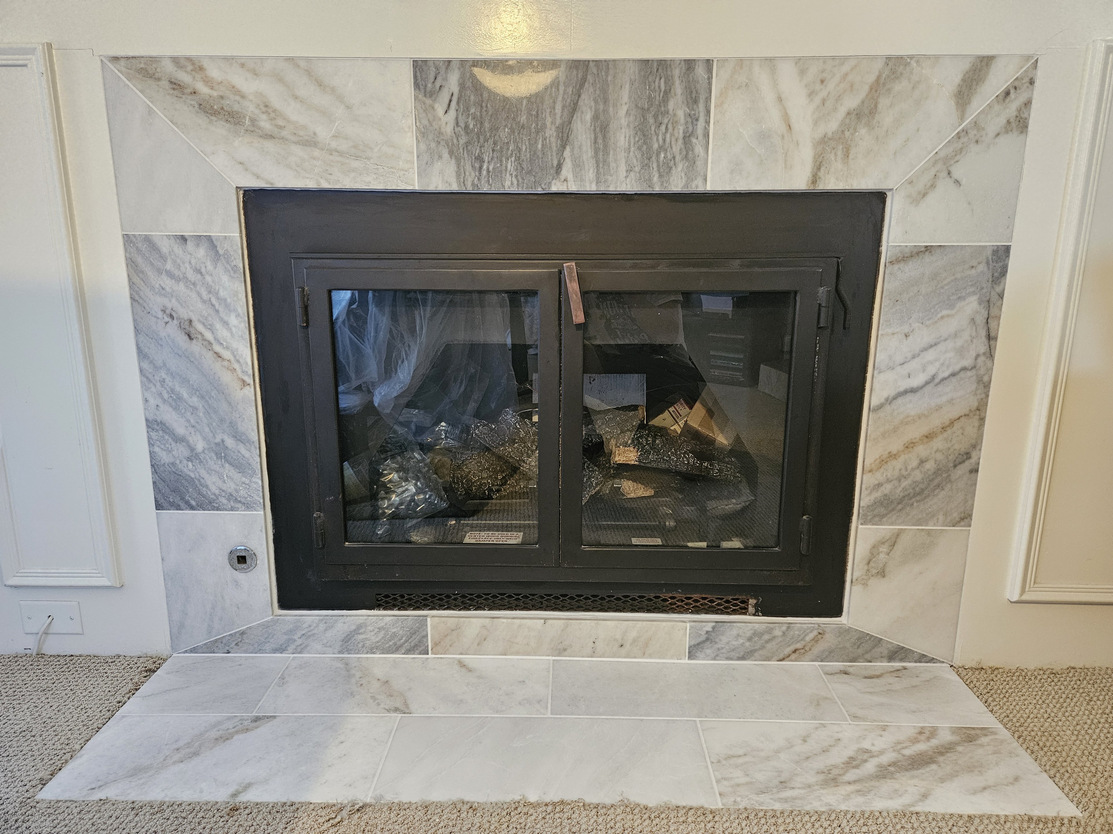 Marble-look tile fireplace surround with clean miters and a raised hearth.